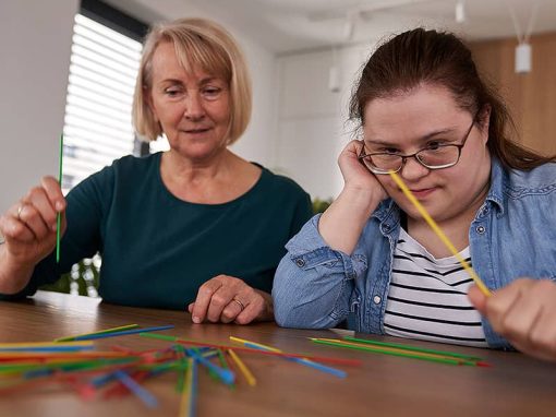 Jobs in der Assistenz: Karriere bei PAT gGmbH Düsseldorf. Assistentin mit einer Klientin bei einem Spiel am Tisch.